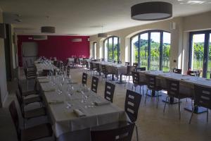 a dining room with tables and chairs and windows at SPA Roero Relax Resort in Canale
