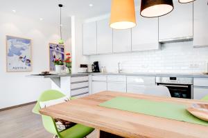 a kitchen with a wooden table and white cabinets at Appartement Valbona Blick by A-Appartments in Bürserberg