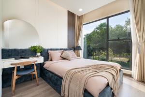 ein Schlafzimmer mit Bett, Schreibtisch und Fenster in der Unterkunft Luxury 3BR Apartment 121m - Resort Pool & Gym - Near Aeon Mall in Ho-Chi-Minh-Stadt