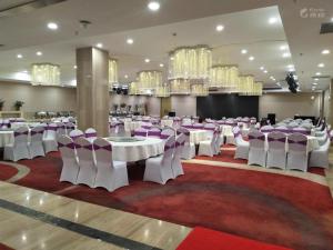 a banquet hall with white tables and chairs and chandeliers at James Joyce Coffetel Qinhuangdao Taiyangcheng Wenhua Road in Qinhuangdao