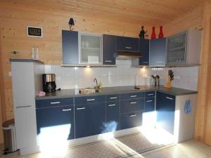a kitchen with blue cabinets and a white refrigerator at Chalet in Ötztal near Ötz-Hochötz Ski Resort in Umhausen