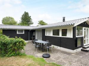 a black house with a table and chairs at 6 person holiday home in Dannemare-By Traum in Dannemare +10 photos