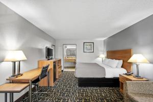 a hotel room with a bed and a desk and a bed and a television at Quality Inn Bowling Green South in Bowling Green