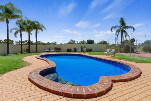 a swimming pool with a brick pathway around it at Comfort Inn & Suites Riverland in Barmera