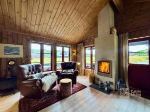 a living room with two chairs and a fireplace at Modern cabin sauna, BBQ & beautiful view Filefjell in Tyinkrysset