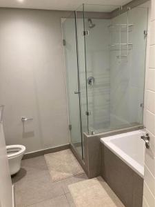 a bathroom with a shower and a tub and a toilet at Pebble Beach 204 in Sibaya