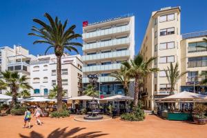 people walking in front of a hotel with palm trees at URH Excelsior in Lloret de Mar