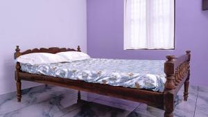 a bed with a wooden frame in a room with a window at Leland Homestay in Mararikulam