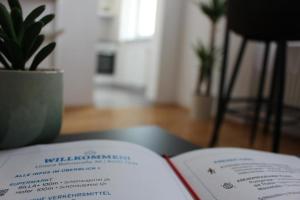 un livre ouvert sur une table avec une plante en pot dans l'établissement Moderne & zentrale Citywohnung nahe Stadthalle, Messe & Sportpark, à Graz