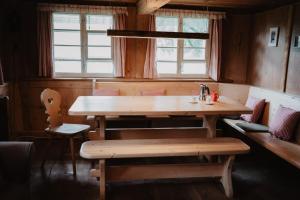 a wooden table and bench in a room with windows at Romantisches Schwarzwälder Bauernhäuschen Hüsli am Griesbachhof in Titisee-Neustadt