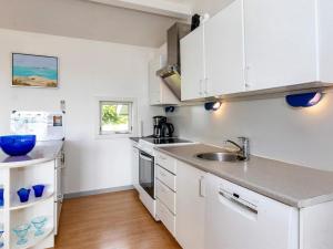 a kitchen with white cabinets and a sink at Seaside Charm in Nature - By Traum Ferienwohnungen in Helberskov