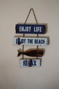 una señal que dice disfrutar de la vida y disfrutar de la playa en 28 Kabeljauws, en Jeffreys Bay