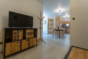 a living room with a flat screen tv on a entertainment center at Gîtes de l'Orée du Bois - Torpes in Torpes