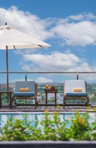 two chairs and an umbrella next to a pool at Little Oasis - An Eco Friendly Hotel & Spa in Hoi An