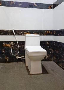 a white toilet in a bathroom with a shower at Leland Homestay in Mararikulam