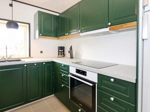 a green kitchen with white counters and green cabinets at 6 person holiday home in Hadsund in Hadsund