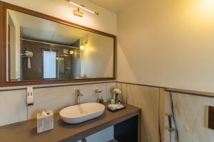 a bathroom with a sink and a large mirror at Villa Lumi, Villas By Noor in Aldona +19 photos