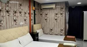 a hotel room with two beds and a couch at New Rawang Hotel in Kuala Lumpur