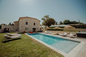 a swimming pool in front of a house with chairs and anophethritisthritisthritis at Le Mas des vignes - Piscine - Jacuzzi - 18 pers in Cazes-Mondenard