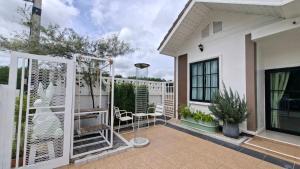 a balcony of a house with a fence and chairs at Baanjaifu บ้านใจฟู in Ban Muang Ba