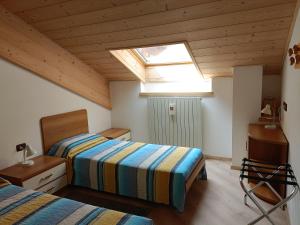 a bedroom with two beds and a skylight at Dolomiti Appartamento Ivano in Predazzo