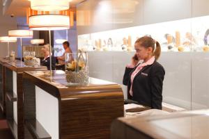 
a woman standing at a counter in a restaurant at AZIMUT Hotel Olympic Moscow in Moscow
