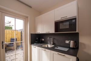 a kitchen with a sink and a microwave at Luxe Kamer - Strand & Zee in Zoutelande