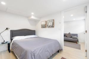 a white bedroom with a bed and a couch at Callister BNB in Vancouver