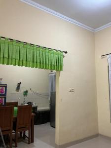 a dining room with a green curtain and a table at Raphi house in Demangan