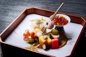 a tray of food with sushi and fruit on a table at Ryokan Asukasou at the entrancne of Nara park in Nara