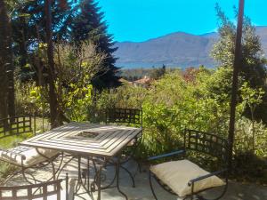 een terrastafel en stoelen met bergen op de achtergrond bij Appartamento Ibisco in Porto Valtravaglia