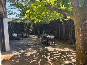 a patio with a table and benches under a tree at Vacances au lac ! in Biscarrosse +2 photos