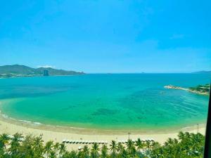 a view of a beach with palm trees and the ocean at Seahome Beachfront Apartment - Mường Thanh Viễn Triều Nha Trang in Nha Trang