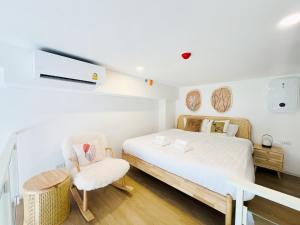 a bedroom with a white bed and a chair at Siamese Residence Landmark MRTA Station Bangkok in Bangkok