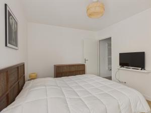 a white bedroom with a large bed and a flat screen tv at Plein centre - Appart pour 6 avec balcon in La Teste-de-Buch +8 photos