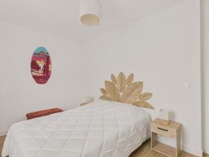 a bedroom with a white bed with a plant on the wall at Plein centre - Appart pour 6 avec balcon in La Teste-de-Buch