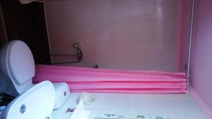 une cabine de douche rose et des toilettes dans la salle de bains. dans l'établissement Studios Lefkada, à Sívros