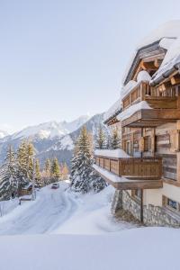 una baita di tronchi nella neve con montagne sullo sfondo di Chalet Montanum, 9 pax - Courchevel, Bed & Breakfast a Courchevel