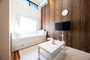 een woonkamer met een witte bank en een tv bij Residence Noa 101 in Fukuoka