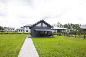 a house with a green lawn in front of it at Berģu Skati, RESTBOAT in Berģi