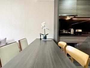 Una mesa de comedor con un jarrón de flores encima. en Klass Langsuan Condo, en Bangkok