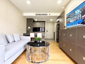 Una sala de estar con un sofá blanco y una mesa. en Klass Langsuan Condo, en Bangkok