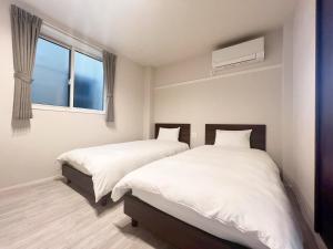 Dos camas en un dormitorio con ventana. en PRISM Inn Tateishi, en Tokio