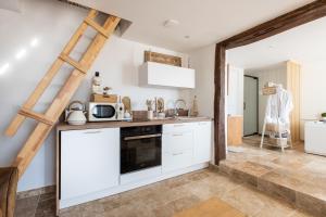 una cucina con armadietti bianchi e una scala a pioli di Le Domaine des Amours - Jacuzzi Privé a Saint-Josse