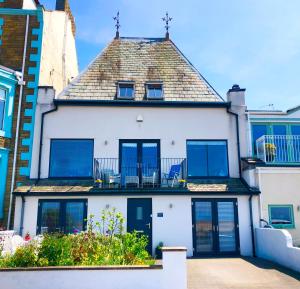 莫克姆Sunsets, Sandylands Prom Morecambe的一栋白色房子，蓝色窗户，屋顶