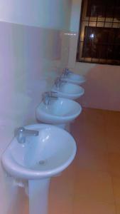 a row of white sinks in a bathroom at Kyanga Hostel in Arusha