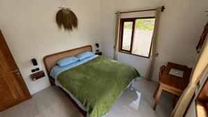 a bedroom with a bed with a green blanket and a window at Ameni Villa in Kuta Lombok