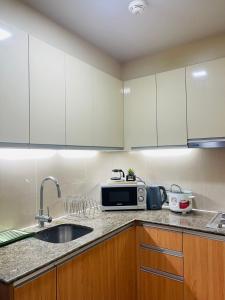 a kitchen with white cabinets and a sink and a microwave at The Mactan Beach Condo Staycation in Punta Engaño