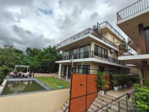 una casa con piscina y gente sentada en el patio en Nuwara Eliya Karjat - 5BHK Villa, en Karjat