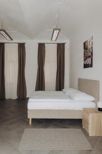 a bedroom with a white bed and brown curtains at Sleep & Go Czech Republic - Praha 5 Anděl in Prague